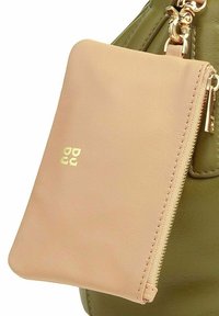 Grüne Handtasche mit einem weichen, braunen Leder-Reißverschlusspouch. Der Pouch hat ein dezentes, geprägtes Logo in Gold und eine glatte, strukturierte Oberfläche.