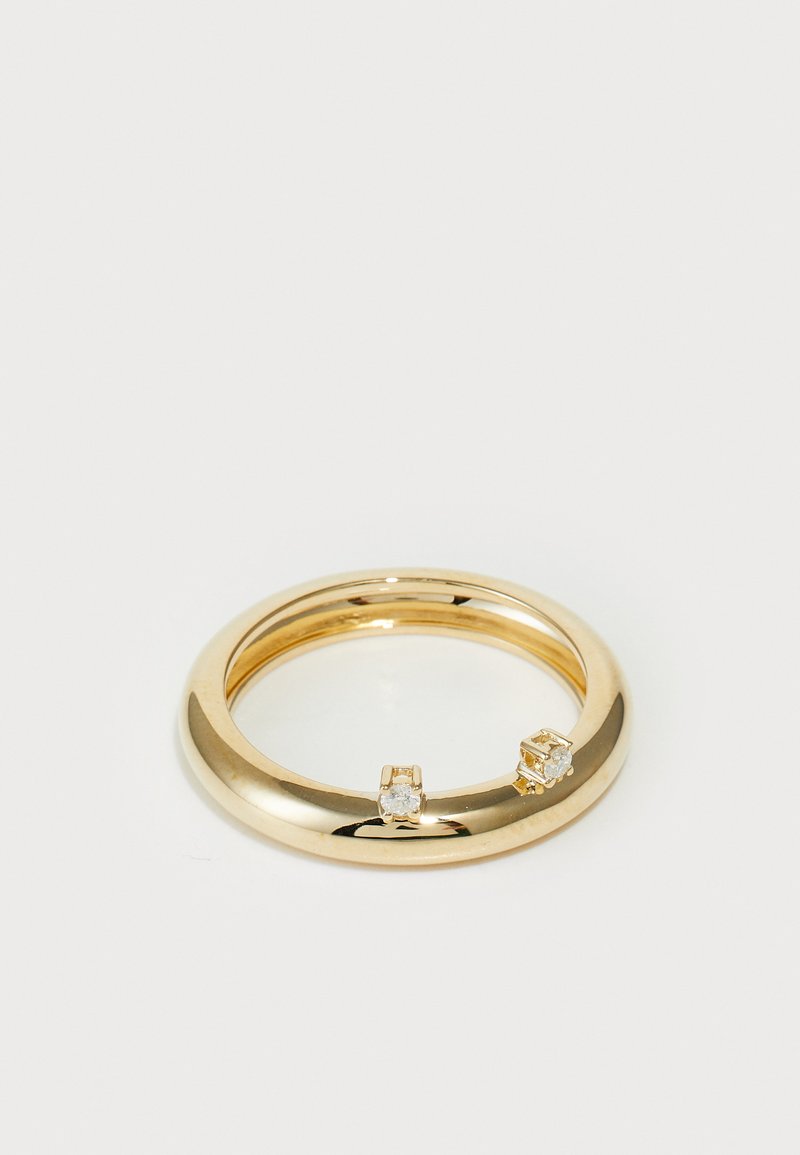 Inel din aur cu finisaj neted, lustruit, având două pietre prețioase clare amplasate pe laturi opuse. Formă rotundă, design solid, textură lucioasă.