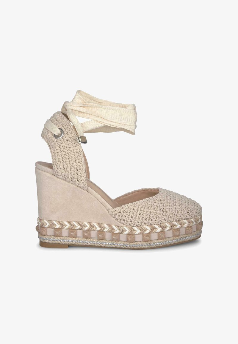 Espadrille compensée beige avec un dessus en textile tissé, un talon en cuir suédé et une bride de cheville en tissu. Présente une semelle en jute tressé.