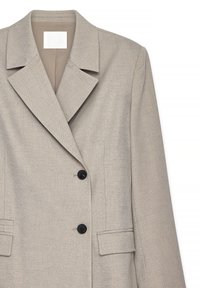 Beige maßgeschneiderter Blazer mit breiten Revers, zwei schwarzen Knöpfen und vorderen Klappentaschen, auf einem weißen Hintergrund präsentiert.