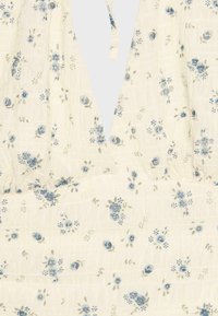 Tissu crème avec fond texturé et petit imprimé floral bleu, doté d'un décolleté en V profond et d'un détail de ceinture froncée.