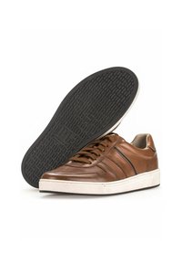 Sneaker en cuir marron avec semelle blanche, semelle extérieure en caoutchouc noir texturé et bandes latérales. Dispose d'un design classique à lacets et d'un col rembourré.