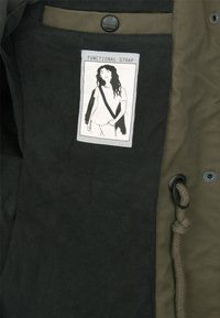 Patch sur tissu noir montrant une femme aux longs cheveux portant une bandoulière de sac en diagonale, étiqueté "Functional Strap."