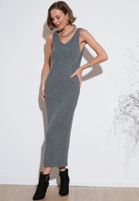 Gray, ribbed knit midi dress with a V-neckline and sleeveless design, paired with black booties featuring a gold buckle accent.