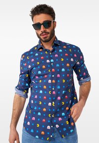 Morska srajca z barvitimi liki Pac-Man in pikami, oblikovana za zapenjanje, dolge rokave z zavihanimi manšetami in gladko teksturo.