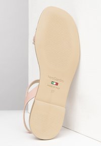 Sandal de color rosa claro con un acabado suave, que presenta una suela de goma beige marcada con estrías. Incluye un logotipo metálico y detalle de tamaño 37.
