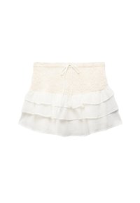 Falda blanca de capas con una capa superior texturizada y cintura elástica, superpuesta con una tela suave y ligera. Detalle de dobladillo con volantes.