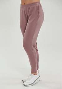 Ljust rosa joggers i mjukt, stretchigt material har en avslappnad passform, elastisk midja och sidofickor. Kombineras med vita sportskor.