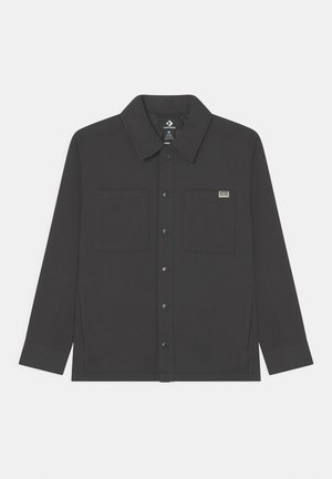 Chemise veste noire boutonnée avec deux poches avant, léger éclat subtil et col. Fabriquée en tissu doux avec une coupe structurée.