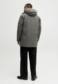 Hall griit vettpidav parka kapuutsiga, millel on sile tekstuur, keskmine pikkus ja sirge lõige. Kandmiseks mustade pükstega ja kingadega.