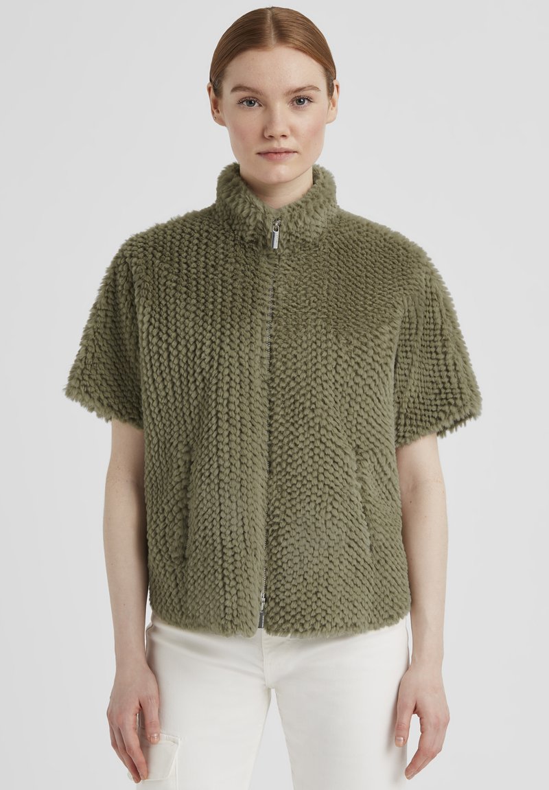 Kurze Ärmel Zip-Jacke aus olivgrünem Kunstfell mit hohem Kragen und strukturierten Oberflächen mit diagonalen Mustern.