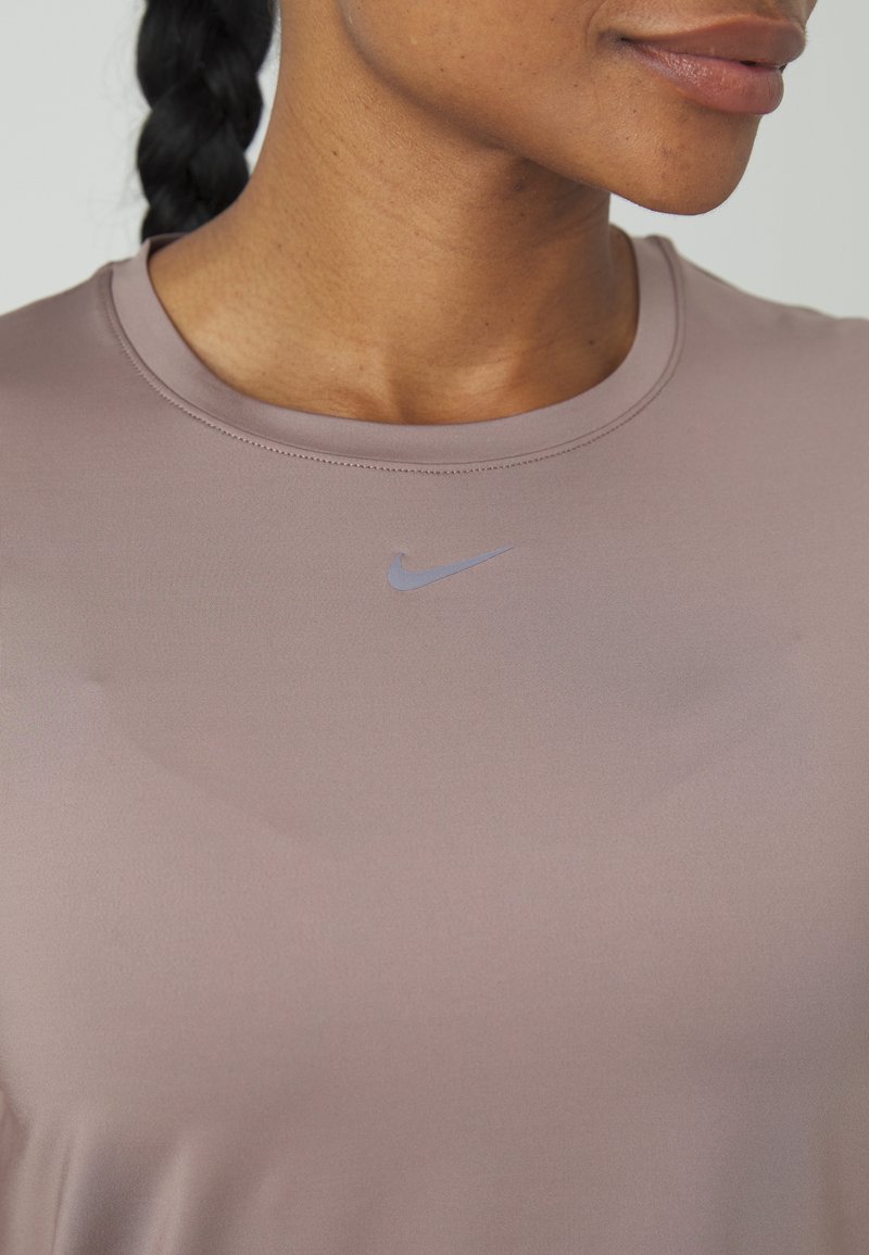 Roze sportshirt met een ronde hals en korte mouwen. Bevat een klein lichtblauw Nike-logo op de borst. Glad textuur.