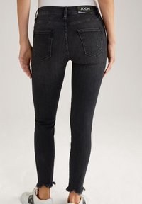 Jean noir à coupe slim, avec un ourlet effiloché et deux poches arrière. Le matériau est légèrement extensible ; logo "JOOP!" sur la ceinture.