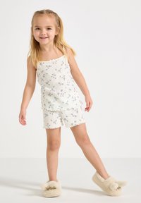 Kevyt valkoinen toppi ja shortsit, joissa on sininen kukkakuosi, ribattu pinta ja taittuvat reunat. Yhdistettyjä kermaisiin pupuaiheisiin tohveleihin.