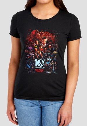 Black t-shirt with colorful Stranger Things 10th anniversary graphic featuring main characters and monsters from the series.