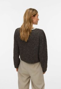 Tumši pelēks īss džemperis no mīksta, teksturēta auduma ar pērļu akcentu pie kakla un garām piedurknēm.