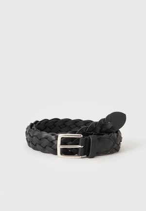 Ceinture en cuir tressé noir avec boucle en métal argenté, enroulée sur un fond clair uni.
