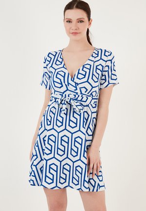 Short-sleeved wrap dress in white fabric featuring a blue geometric pattern; includes a fabric tie at the waist and a V-neckline.