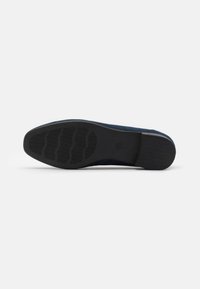 Zapato de ante azul marino con suela de goma negra plana que presenta líneas de agarre texturizadas y una punta lisa. El interior es de un azul profundo a juego.