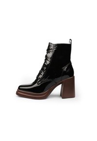 Botines negros con cordones, con un upper de charol, tacón cuadrado marrón grueso y caña texturizada que presenta acentos brillantes en contraste.
