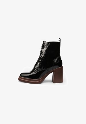 Zwarte veterschoenen tot de enkel met een bovenwerk van lakleer, een chunky bruine blokhak en een gestructureerde schacht met contrasterende glanzende accenten.