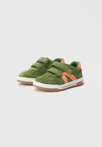 Grønne sneakers i semsket skinn med to borrelåsremmer, oransje detaljer, hvit gummisåle og teksturert mønster langs sidene.