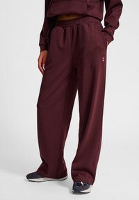 Bordeaux sweatpants met een relaxte pasvorm, elastische tailleband, zijzakken en een klein roze chevronlogo op het linkerpoot. Zachte textuur.
