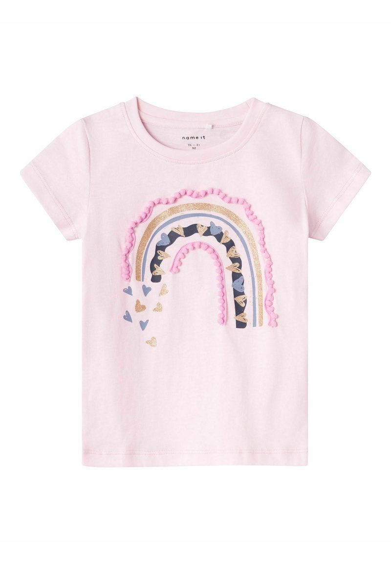 Camiseta de manga corta en color rosa claro, con un diseño de arco iris multicolor adornado con flecos de pompones y acentos en forma de corazón en varios colores.