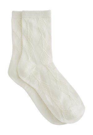 Par de calcetines tobilleros blancos con un sutil patrón de punto de diamante y puño acanalado, mostrados planos y superpuestos sobre un fondo blanco.