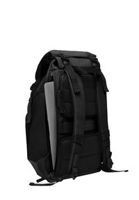 Sac à dos noir en tissu durable avec des compartiments rembourrés, des bretelles ajustables et une poche latérale pour un ordinateur portable. Texture lisse.