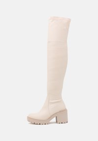 Bottes hautes jusqu'au genou en matière synthétique beige douce. Talon épais avec semelle texturée, design épuré et tige sans coutures pour un look lisse.