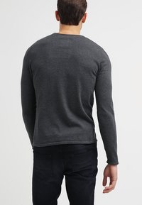 Camiseta de manga larga con cuello redondo, en mezcla de algodón gris oscuro. Presenta un diseño ajustado con un dobladillo recto y detalles mínimos de costura en el escote.