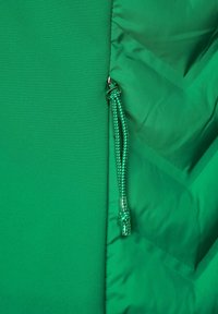 Groen textiel met gladde en gestructureerde secties, voorzien van een ritssluiting met een gevlochten trekkoord. Eenvoudig ontwerp zonder zichtbare patronen.