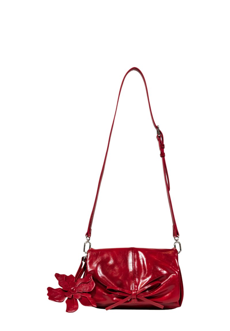 Borsa a tracolla in pelle rossa con un design morbido, dettaglio a fiocco e un accento floreale. Presenta una lunga tracolla regolabile e hardware in metallo.