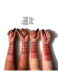 Trzy ręce prezentują różne próbki matowych pomadek w płynie w odcieniach różu i nude. Każda ręka trzyma tubkę produktu z czarną nakrętką.