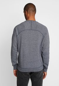 Sudadera gris para hombre en tejido texturizado, con un cuello redondo, mangas largas y un diseño de canesú curvado en la parte posterior.