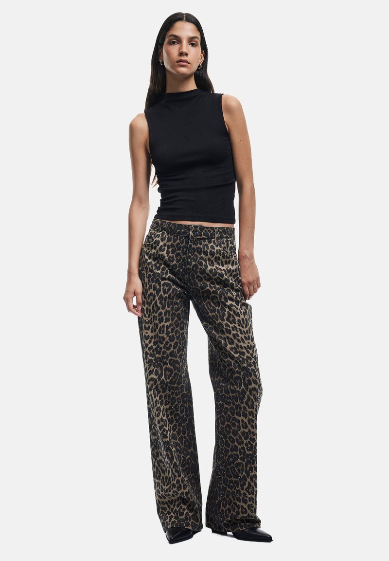 Top negro sin mangas combinado con pantalones anchos de estampado de leopardo. La tela tiene una textura suave con un atrevido patrón animal y tonos neutrales.