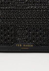 Portafogli in tessuto intrecciato nero di Ted Baker, con un motivo testurizzato e dettagli del logo in oro. Accenti in pelle nera liscia.