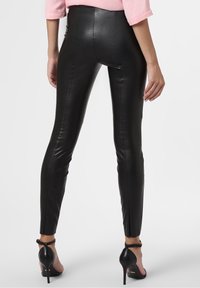 Svarta leggings i konstläder med hög midja, med släta sömmar längs sidorna och en mjuk, blank yta.