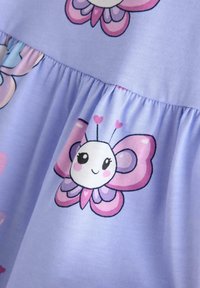 Leende tecknad fjäril med rosa och lila vingar och hjärtformade antenner på lavendelfärgat tyg med veckad söm.