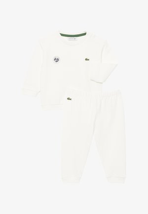Weißes Set aus langärmeligem Oberteil und Hose mit grünen Lacoste Krokodil-Logos und einem Roland Garros Turnier-Patch auf dem Oberteil.