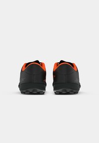 Zapatillas deportivas negras con acentos naranjas, que cuentan con un upper texturizado, un collar acolchado y una suela resistente con tacos de tracción prominentes.