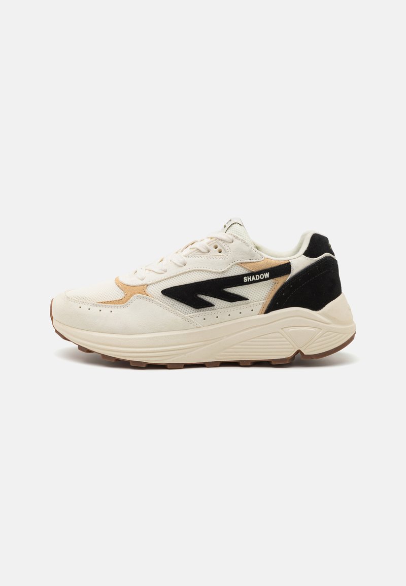 White athletic shoes with beige and black accents, textured material, cushioned sole, and logo detail on the side. Rubber outsole.