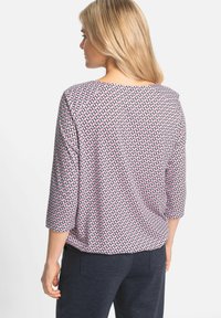 Three-quarter sleeve top featuring a geometric pattern of pink and navy shapes on a light background. Soft fabric with relaxed fit.