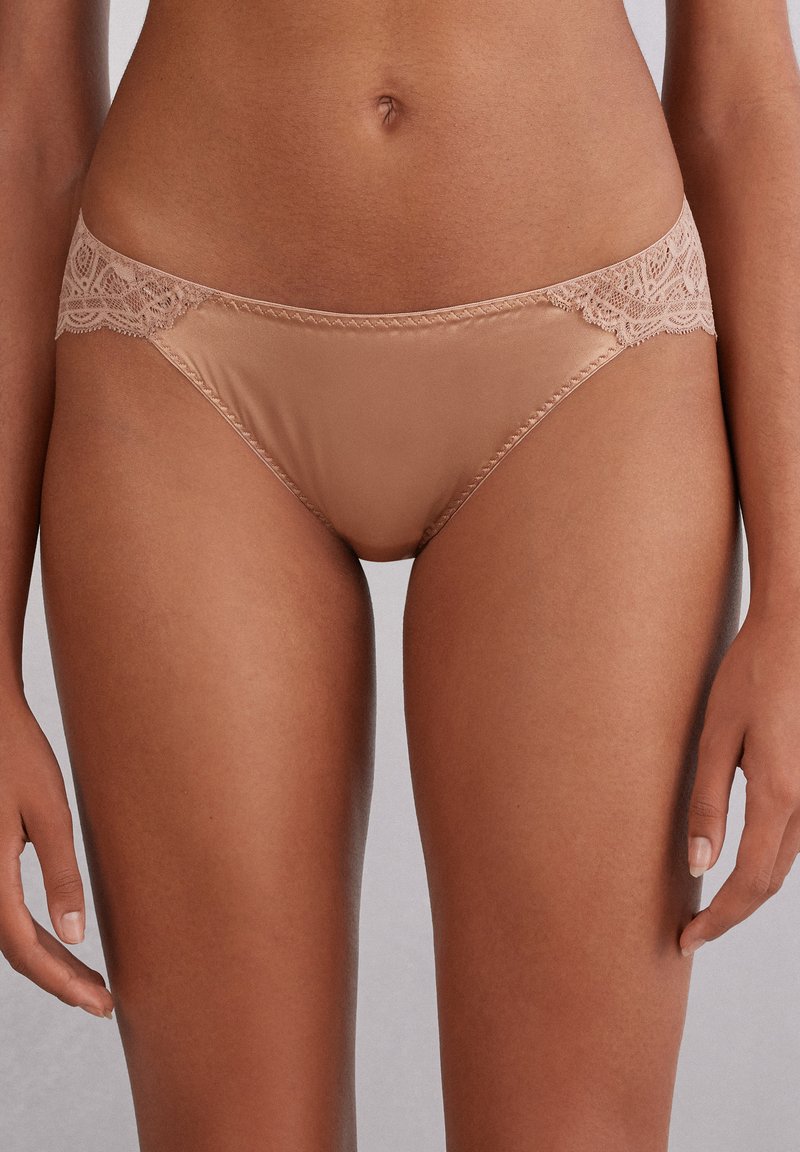 Bikiniunderkläder i beige med spetskant och en slät, satinfinish. Har detaljerad blommig spets på midjebandet som ger en delikat accent.