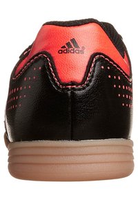 Schwarzer und roter Sportschuh mit glattem Lederobermaterial, strukturierten Einsätzen, Gummisohle und Drei-Streifen-Logo an der Ferse.