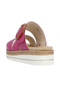Sandal in pelle rosa con retro aperto e cinturini incrociati, dotata di una fibbia tonda marrone, soletta imbottita e suola piatta bianca.