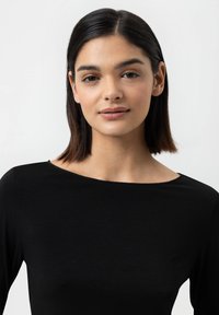 Haut à manches longues noir avec un large col, texture lisse et design ajusté. Style simple et minimaliste.