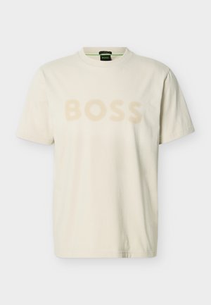 T-shirt a maniche corte in cotone color crema con logo testuale "BOSS" in beige chiaro sul petto e scollo rotondo.