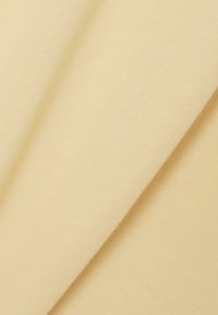 Tela beige claro y suave con una textura lisa y de tejido apretado, mostrada en un arreglo doblado con delicadeza.